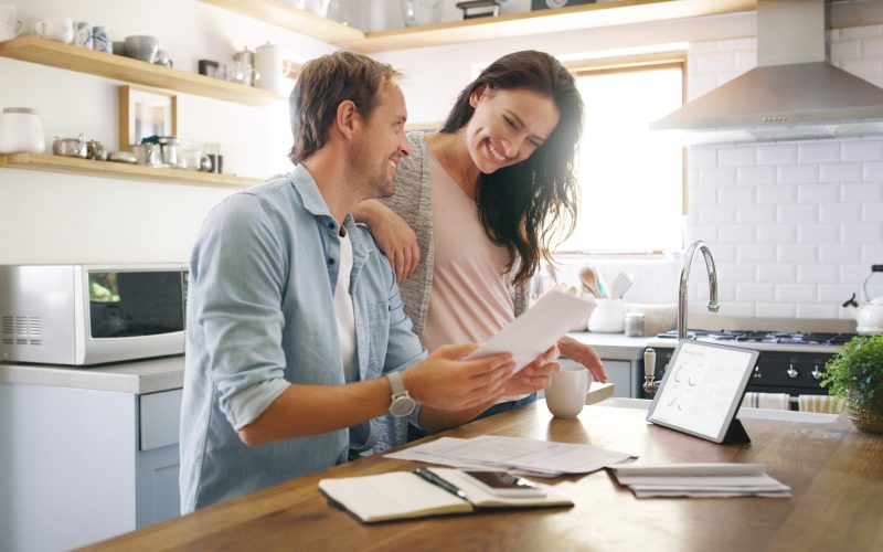 Couple, happy and tablet with documents at house for financial planning, bank balance and debt payment. Man, woman and paperwork for budget savings, property insurance and credit score of mortgage.